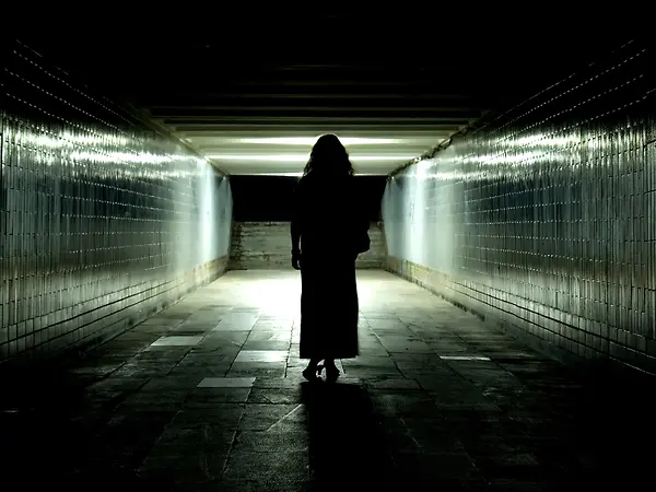 Aktuelle Psychotriller 2025: Eine Person steht als Silhouette in einem dunklen Tunnel mit Licht am Ende.