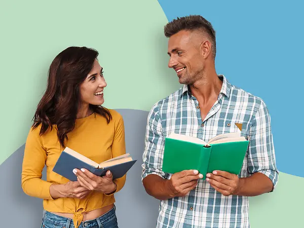 Ein Mann und eine Frau mit Büchern in der Hand schauen sich freundlich an